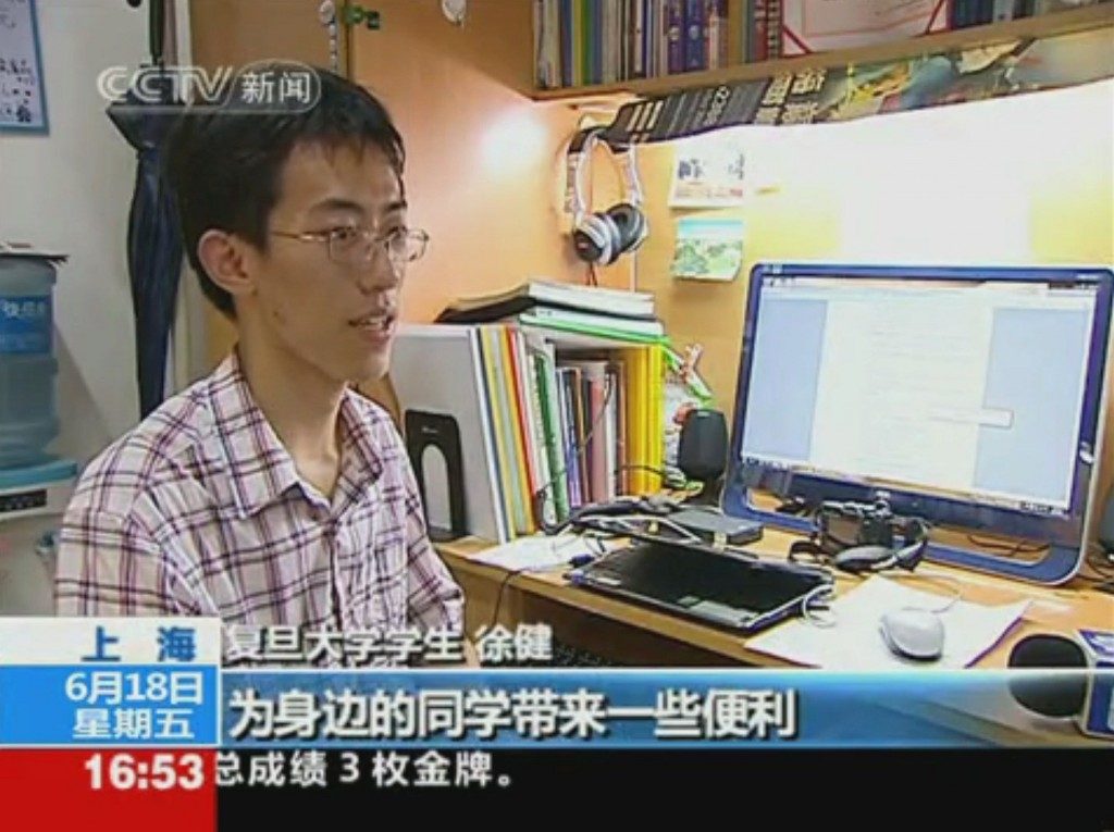 A CCTV news frame of Jian Xu at his desk in the dorm, with a Chinese caption.
