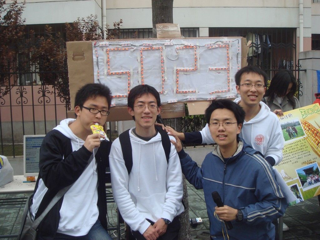 Four students under a hand-built LED sign reading 5023.